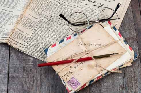 eyeglasses on newspaper beside mail envelops